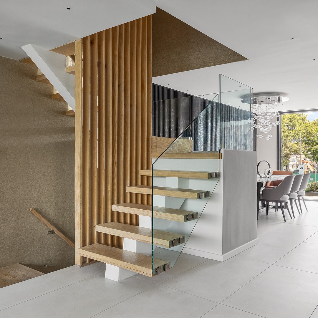 Escalera flotante con barandal de vidrio y madera clara