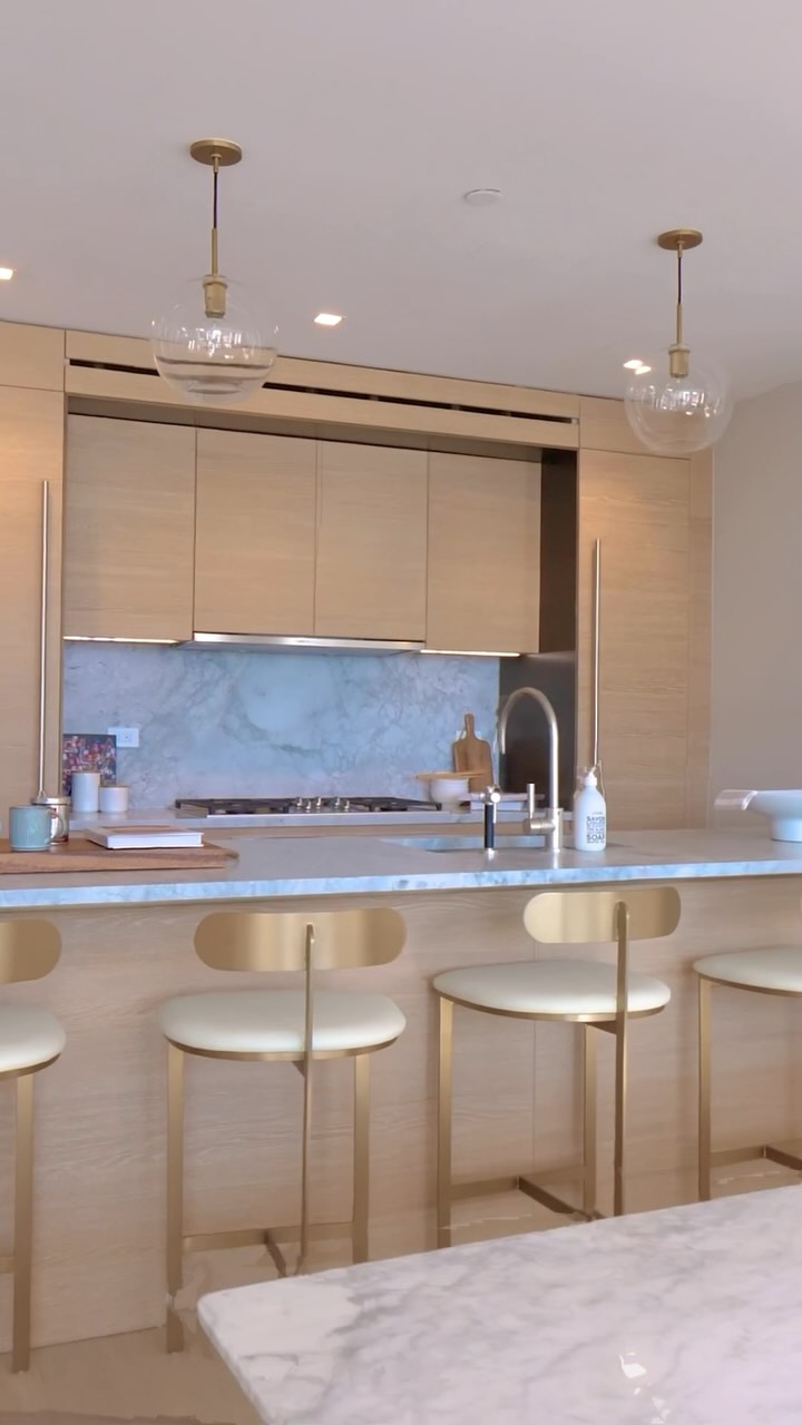 Cocina de lujo con gabinetes de fresno claro y bancas de diseñador doradas